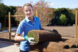 Woman holding a roll of turf to lay new lawn