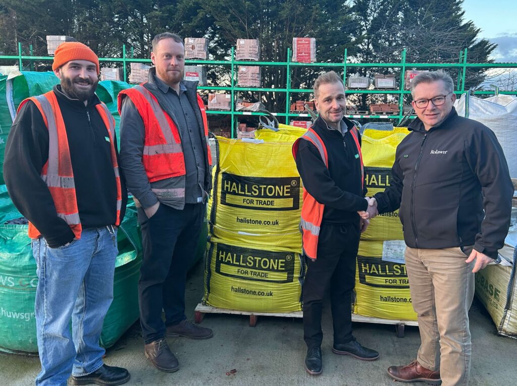 Jonathan Hill, Hallstone Sales & Marketing Director shakes hands with Robin Hollingworth of Huws Gray, in front of Hallstone bulk bags.